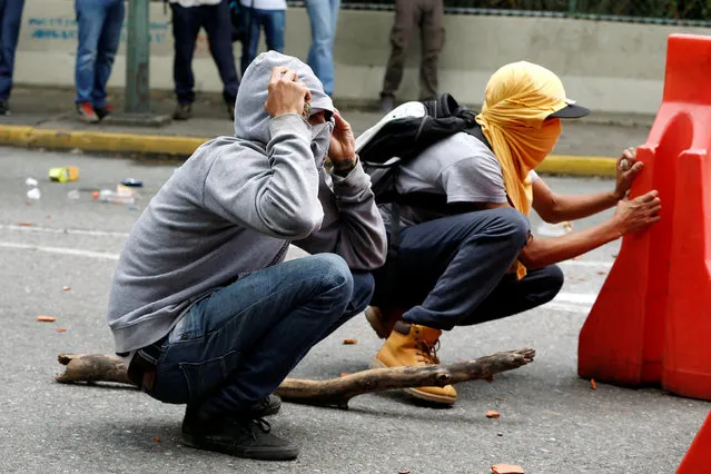 Demonstrators take cover as they clash with riot police officers during a protest called by university students against Venezuela's government in Caracas, Venezuela, June 9, 2016. (Photo by Carlos Garcia Rawlins/Reuters)