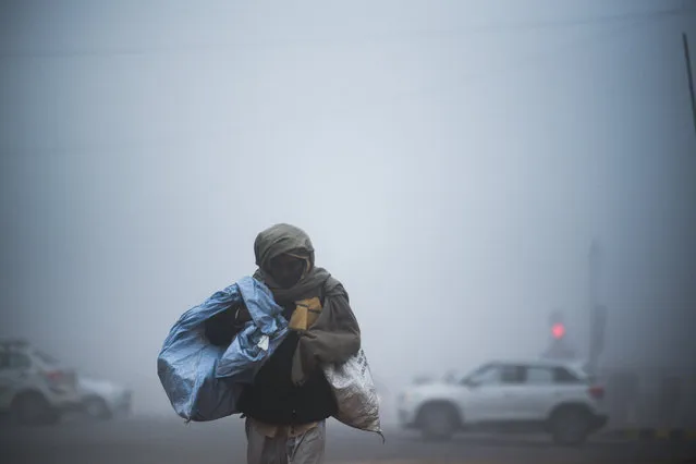 A man crosses a street under heavy foggy conditions in New Delhi on December 30, 2019. (Photo by Jewel Samad/AFP Photo)