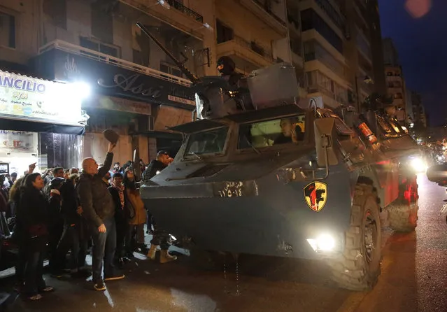 A police armored personnel carrier passes next of anti-government protesters outside police headquarters, as they demand the release of those taken into custody the night before, in Beirut, Lebanon, Wednesday, January 15, 2020. Lebanese security forces arrested 59 people, the police said Wednesday, following clashes overnight outside the central bank as angry protesters vented their fury against the country's ruling elite and the worsening financial crisis. (Photo by Hussein Malla/AP Photo)