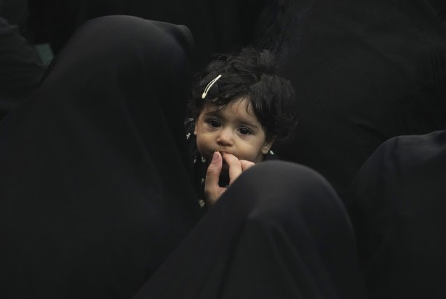 An Iranian Shiite Muslim woman feeds her child as they attend Ashoura mourning ritual, commemorating the 7th century martyrdom of Prophet Muhammad's grandson, Hussein, in the battle of Karbala in present-day Iraq, at the old main bazaar of Tehran, Iran, Tuesday, July 16, 2024. Shiites represent over 10% of the world's 1.8 billion Muslims and view Hussein as the rightful successor to the Prophet Muhammad. (Photo by Vahid Salemi/AP Photo)