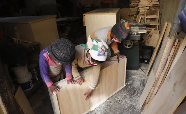 Three of the Delgado children, from right, Yuri, 11, Wendi, 9, and Alison, 8, make a drawer in the family carpentry workshop in El Alto, Bolivia, Wednesday, September 2, 2020. In a country where informal employment makes up 70% of the economy, the closure of schools because of the new coronavirus pandemic puts more kids like the Delgados to work. (Photo by Juan Karita/AP Photo)