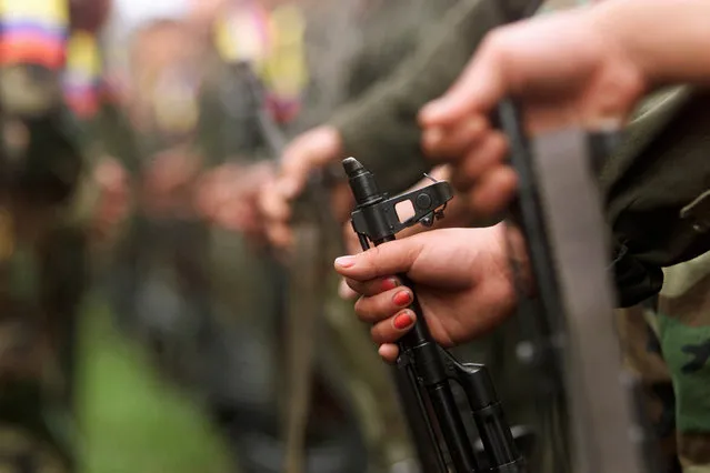 A Colombian guerilla woman holds her AK-47 as she takes part in a line of rebels during an army parade of fighters of the FARC in Villa Colombia camp near San Vicente del Caguan, Caqueta province, Colombia, April 29, 2000. (Photo by Jose Miguel Gomez/Reuters)