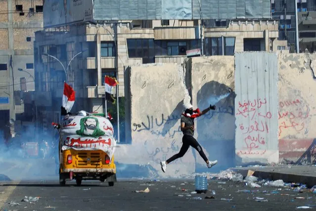 A demonstrator throws away a tear gas canister during an anti-government protests in Baghdad, Iraq on November 1, 2019. (Photo by Khalid al-Mousily/Reuters)