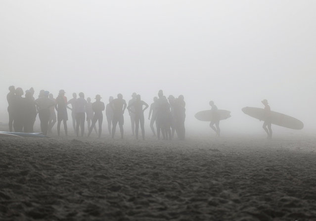 People gather on Muizenberg beach in the early morning as seasonal mist shrouds the sun in Cape Town, South Africa, on April 18, 2024. (Photo by Esa Alexander/Reuters)