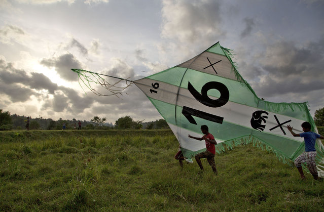 Supporters of Sri Lanka's ruling United National Party run with a giant kite displaying the party colors and symbol ahead of Parliamentary Election in Gampaha, east of Colombo, Sri Lanka, Friday, August 14, 2015. Sri Lanka's Parliamentary Election is scheduled to be held on August 17, 2015. (Photo by Gemunu Amarasinghe/AP Photo)