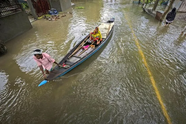 A flood affected villager rows his boat on a flooded road in Tarabari village, west of Gauhati, in the northeastern Indian state of Assam, Monday, June 20, 2022. (Photo by Anupam Nath/AP Photo)