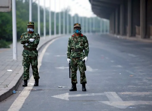 Paramilitary policemen wearing masks stand guard on a road leading to the evacuated residential area and explosion site at Binhai new district in Tianjin, China, August 17, 2015. (Photo by Kim Kyung-Hoon/Reuters)
