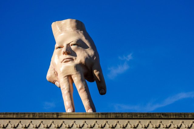 A 16-foot- ( almost 5 meters ) tall hand sculpture named Quasi stands perched on its fingertips atop the roof of an art gallery in Wellington, New Zealand, Wednesday, October 30, 2024. (Photo by Charlotte Graham-McLay/AP Photo)