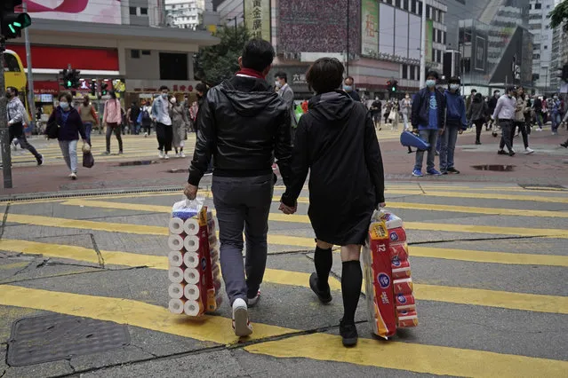 A couple carry a supply of toilet paper at a street on Valentine's Day in Hong Kong, Friday, February 14, 2020. (Photo by Kin Cheung/AP Photo)