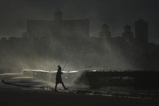 A person fishes along the boardwalk as waves crash during a power outage in Havana, Monday, October 21, 2024. (Photo by Ramon Espinosa/AP Photo)