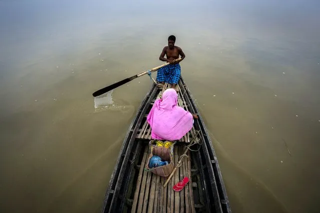 A man rows his boat to ferry a woman across an island in the river Brahmaputra on the outskirts of Gauhati, Assam state, India, Friday, July 8, 2022. Brahmaputra is one of Asia's largest rivers, which passes through China's Tibet region, India and Bangladesh before converging into the Bay of Bengal. (Photo by Anupam Nath/AP Photo)