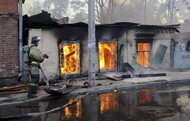 A firefighter works to put out a blaze at houses in Rostov-on-Don, Russia, Monday, August 21, 2017. Hundreds of firefighters backed by helicopters were deployed to extinguish the blaze that engulfed dozens of buildings. (Photo by AP Photo)