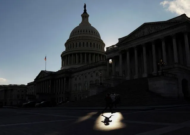 A jogger passes through a beam of sunlight in front of the U.S Capitol in Washington, U.S., January 18, 2022. (Photo by Kevin Lamarque/Reuters)