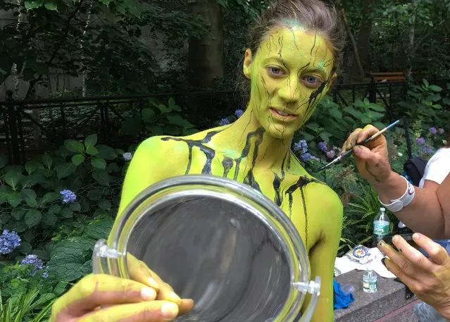 Megan Slawkawski looks at her reflection as bodypainter artist Uta Brauser applies paint at the third annual NYC Bodypainting Day on Saturday July 9, 2016, New York. Dozens of artists used the naked bodies as canvases for the event, which celebrates freedom of artistic expression and body acceptance. (Photo by Dino Hazell/AP Photo)
