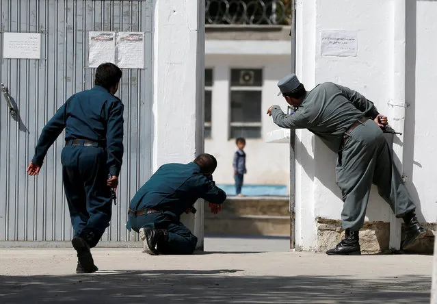 Afghan policemen try to rescue a child at the site of a suicide attack followed by a clash between Afghan forces and insurgents after an attack on a Shi'ite Muslim mosque in Kabul, Afghanistan on Friday, August 25, 2017. (Photo by Omar Sobhani/Reuters)