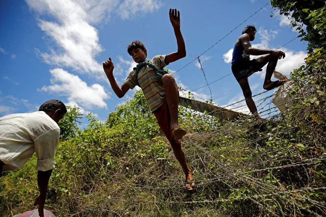 A Rohingya boy jumps over the border fence to enter inside Bangladesh border, in Cox’s Bazar, Bangladesh, August 27, 2017. (Photo by Mohammad Ponir Hossain/Reuters)
