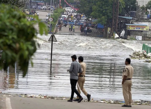 Policemen watch a road inundated with water from the overflowing Musi river after heavy rainfall in Hyderabad, India, Wednesday, July 27, 2022. (Photo by Mahesh Kumar A./AP Photo)