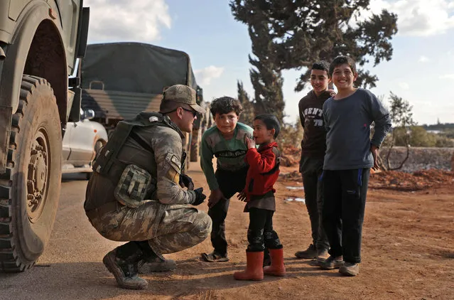 A Turkish soldier speaks to displaced Syrians near the town of Batabu on the highway linking Idlib to the Syrian Bab al-Hawa border crossing with Turkey, on March 2, 2020. The Syrian government pledged to repel Turkish forces attacking its Russia-backed troops in northwestern Syria as tensions spike between Damascus and Ankara. Since December, Syrian regime forces have led a deadly military offensive against the last major opposition stronghold of Idlib, where Turkey supports some rebel groups. Damascus said it shot down three Turkish drones in the region the day before, while two Syrian warplanes were downed though the pilots escaped unharmed. (Photo by Aaref Watad/AFP Photo)
