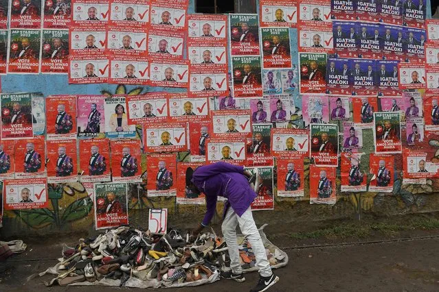 A hawker sells second hand shoes next to campaign posters of various candidates in Nairobi, on August 02, 2022, ahead of Kenya's August 2022 general election. (Photo by Simón Maina/AFP Photo)