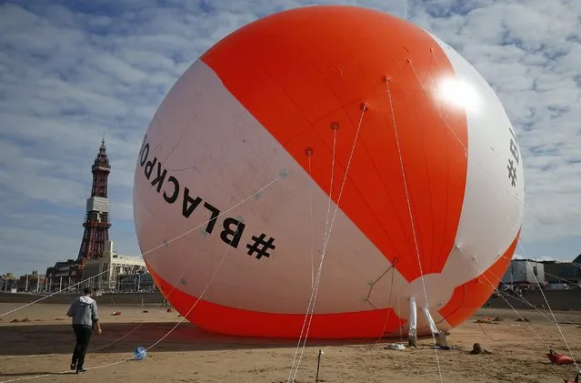 A giant inflated beach ball sits on the sand at Blackpool Beach in Blackpool, northern England August 15, 2014. The ball was inflated to a height of 16.6 meters on Friday, beating the previous world record of 15.8 meters. (Photo by Andrew Yates/Reuters)