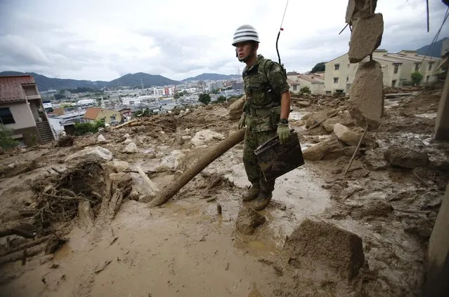 A Japan Self-Defense Force soldier searches for survivors at a site where a landslide swept through a residential area at Asaminami ward in Hiroshima, western Japan, August 20, 2014. At least 36 people, including several children, were killed in Japan on Wednesday, when landslides triggered by torrential rain slammed into the outskirts of the western city of Hiroshima, and the toll could rise further, police said. (Photo by Toru Hanai/Reuters)