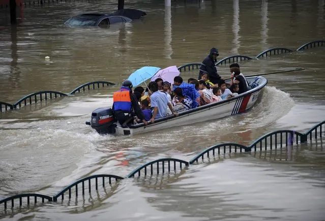 People are transported with a boat along a flooded street as heavy rainfall hits Lishui, Zhejiang province, August 20, 2014. (Photo by Reuters/Stringer)