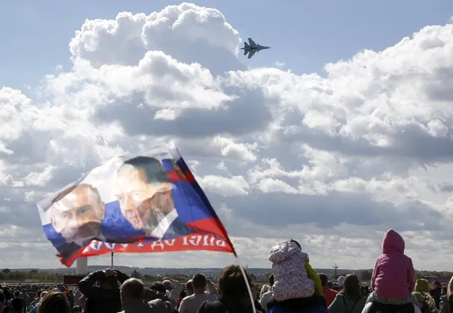 A spectator waves a flag depicting images of Russian President Vladimir Putin (L) and Prime Minister Dmitry Medvedev as a Sukhoi SU-34 fighter-bomber performs during the MAKS International Aviation and Space Salon in Zhukovsky outside Moscow, Russia, August 30, 2015. (Photo by Maxim Zmeyev/Reuters)