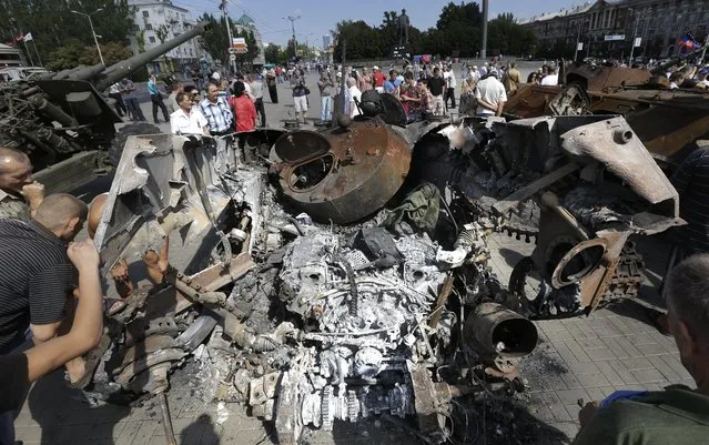 People inspect damaged heavy hardware from the Ukrainian army during an exhibition in a central square in Donetsk, eastern Ukraine, Sunday, August 24, 2014. Ukraine has retaken control of much of its eastern territory bordering Russia in the last few weeks, but fierce fighting for the rebel-held cities of Donetsk and Luhansk persists. (Photo by Sergei Grits/AP Photo)