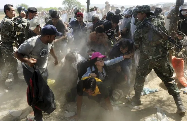 Migrants fall as they rush to cross into Macedonia after Macedonian police allowed a small group of people to pass through a passageway, as they try to regulate the flow of migrants at the Macedonian-Greek border September 2, 2015. (Photo by Ognen Teofilovski/Reuters)