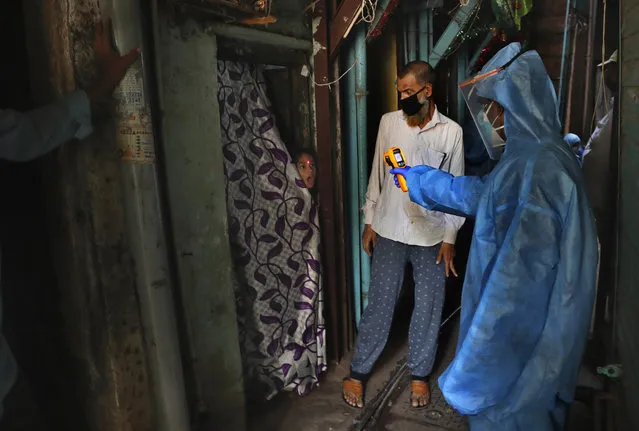 A doctor checks the temperature of a girl in Dharavi, one of Asia's largest slums, during lockdown to prevent the spread of the new coronavirus in Mumbai, India, Monday, April 13, 2020. (Photo by Rafiq Maqbool/AP Photo)