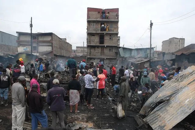 Residents stand on what used to be iron sheet houses that have been razed down by a fire caused by  an electric fault, in Mathare, Nairobi, on August 31, 2022. (Photo by Simon Maina/AFP Photo)