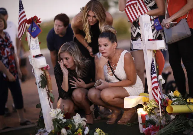 From left, Rachel Shepherd, Jamie Lambert and Annie Leach visit a makeshift memorial for victims of a mass shooting Friday, October 6, 2017, in Las Vegas. Stephen Paddock opened fire on an outdoor country music concert on Sunday killing dozens and injuring hundreds. (Photo by John Locher/AP Photo)