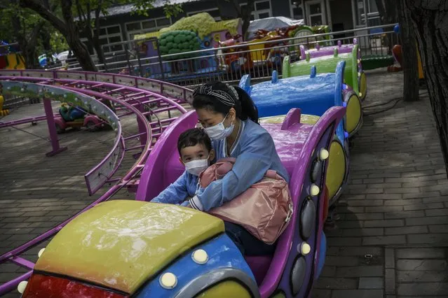 A Chinese woman and boy wear protective masks as they enjoy a ride at a small amusement area that re-opened at a local park during the May holiday on May 4, 2020 in Beijing, China. After decades of growth, officials said Chinas economy had shrunk in the latest quarter due to the impact of the coronavirus epidemic. The slump in the worlds second largest economy is regarded as a sign of difficult times ahead for the global economy. While industrial sectors in China are showing signs of reviving production, a majority of private companies are operating at only 50% capacity, according to analysts. With the pandemic hitting hard across the world, officially the number of coronavirus cases in China is dwindling, ever since the government imposed sweeping measures to keep the disease from spreading. Officials believe the worst appears to be over in China, though there are concerns of another wave of infections as the government attempts to reboot the worlds second largest economy. Since January, China has recorded more than 81,000 cases of COVID-19 and at least 3200 deaths, mostly in and around the city of Wuhan, in central Hubei province, where the outbreak first started. (Photo by Kevin Frayer/Getty Images)