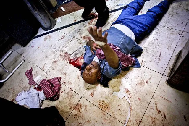 A wounded Syrian man begs for help while lying on the floor of Dar El Shifa hospital in Aleppo, Syria, on October 10, 2012. (Photo by Manu Brabo/Associated Press)