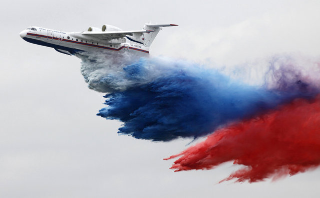 A Russian-made Beriev Be-200ChS amphibious aircraft dumps some 12 tons of coloured water matching the Russian state flag during a demonstration flight at an air show dedicated to the Day of Aviation at the Yemelyanovo airport near Russia's Siberian city of Krasnoyarsk, August 20, 2011. (Photo by Ilya Naymushin/Reuters)