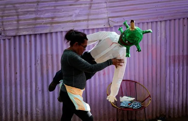 A woman holds a handmade doll depicting Covid-19 Omicron variant in Managua, on December 27, 2021. The dolls are burned at midnight on December 31 as a tradition of saying goodbye to the old year and welcoming the new. (Photo by Oswaldo Rivas/AFP Photo)