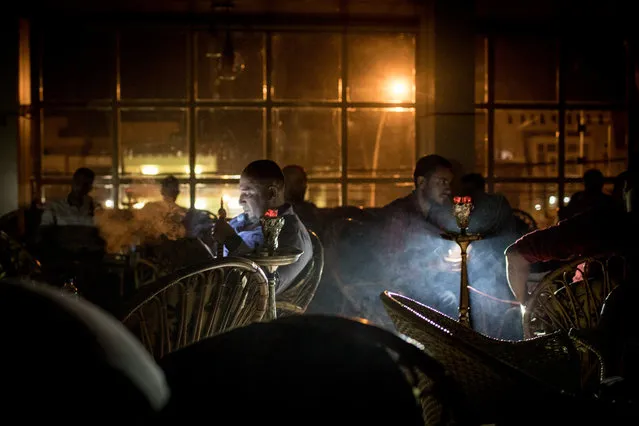 Men smoke waterpipes during a power outage at a cafe in East Mosul on November 5, 2017 in Mosul, Iraq. (Photo by Chris McGrath/Getty Images)
