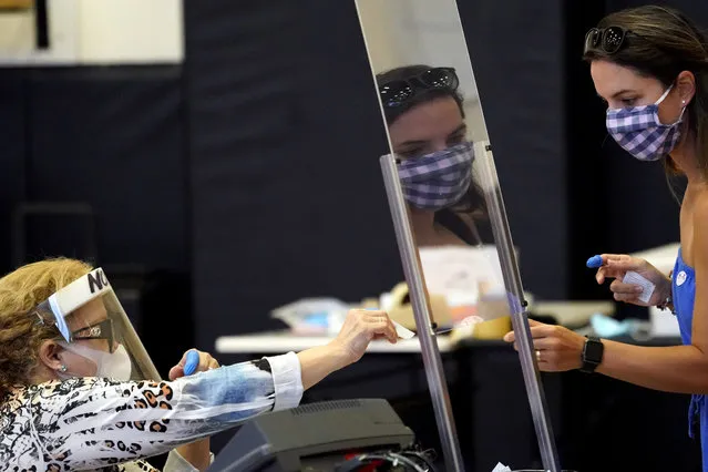 Harris County election clerk Nora Martinez, left, helps a voter, Monday, June 29, 2020, in Houston. Early voting for the Texas primary runoffs began Monday. (Photo by David J. Phillip/AP Photo)