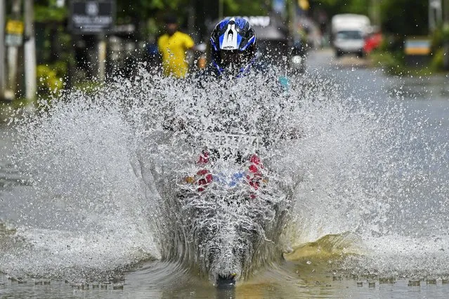 A man rides a motorbike through a flooded street after heavy rains on the outskirts of Colombo on October 16, 2022. (Photo by Ishara S. Kodikara/AFP Photo)
