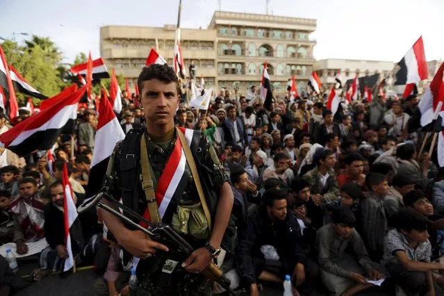 A Houthi militant stands guard as people watch a ceremony marking the first anniversary of the Houthi movement's takeover of Yemen's capital Sanaa September 21, 2015. (Photo by Khaled Abdullah/Reuters)