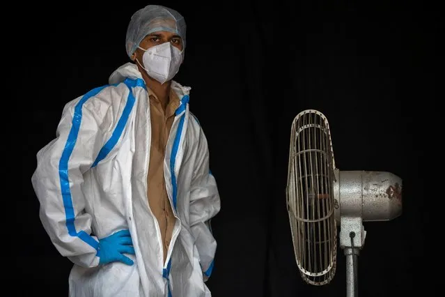 A health worker in personal protective equipment (PPE) takes a break while waiting for people to collect samples to conduct tests for the coronavirus disease (COVID-19), amid the spread of the disease, in New Delhi, India July 10, 2020. (Photo by Danish Siddiqui/Reuters)