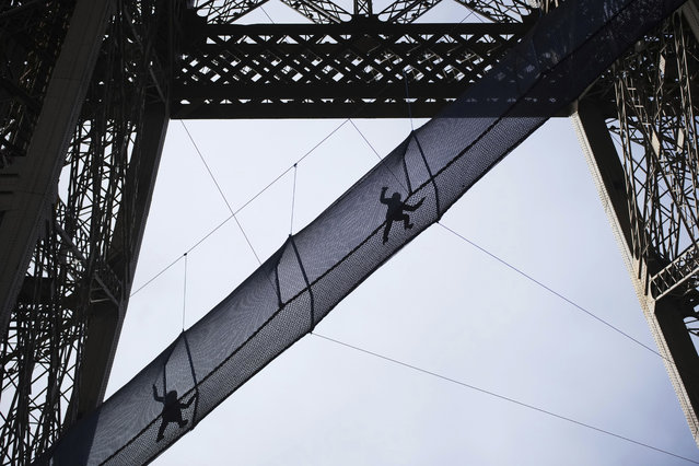 Visitors cross the Vertigo of the Tower, an attraction made of a 40-meter-long bridge at a height of 60 meters designed with nets and set up on the 1st floor of the Eiffel Tower until March, 9, in Paris, Thursday, February 27, 2025. (Photo by Christophe Ena/AP Photo)