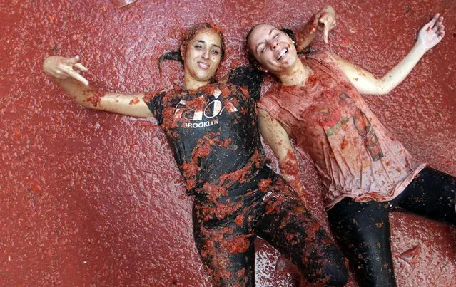 Two girls pose as they lie in a puddle of squashed tomatoes, during the annual “Tomatina”, tomato fight fiesta, in the village of Bunol, 50 kilometers outside Valencia, Spain, Wednesday, August 31, 2016. The streets of an eastern Spanish town are awash with red pulp as thousands of people pelt each other with tomatoes in the annual “Tomatina” battle that has become a major tourist attraction. At the annual fiesta in Bunol on Wednesday, trucks dumped 160 tons of tomatoes for some 20,000 participants, many from abroad, to throw during the hour-long morning festivities. (Photo by Alberto Saiz/AP Photo/ANSA)