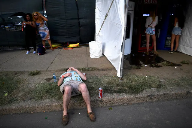 A man sleeps while women withdraw money during the fifth annual Made in America Music Festival in Philadelphia, Pennsylvania September 3, 2016. (Photo by Mark Makela/Reuters)