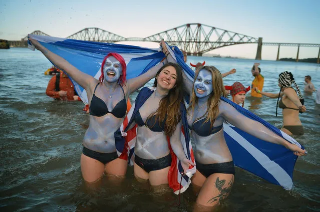 Girls holding saltire flags join around a thousand New Year swimmers, many in costume, who braved freezing conditions in the River Forth in front of the Forth Rail Bridge during the annual Loony Dook Swim on January 1, 2013 in South Queensferry, Scotland. Thousands of people gathered last night to see in the New Year at Hogmanay celebrations in towns and cities across Scotland.  (Photo by Jeff J. Mitchell)