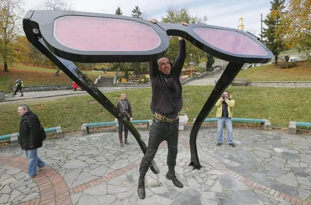 Ukrainian artist Volodymyr Padun, one of authors of the giant pink glasses, hangs on his artwork in Kiev, Ukraine, 24 October 2014. The sculpture named “World Through Pink Glasses” was built by using 800 normal glasses and measures 2,9 meters of height and weighs 250 kg. It is supposed to remind Ukrainians about their dreams, as the authors said. (Photo by Sergey DolzhenkoEPA)