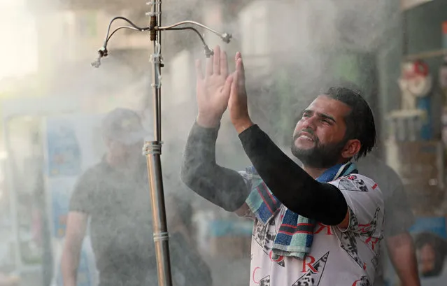 A man cools off from the summer heat under an open air shower in Baghdad, Iraq, Sunday, July 5, 2020. (Photo by Hadi Mizban/AP Photo)