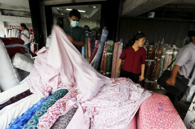 A worker holds a fabric in a shop at Glodok neighborhood in Jakarta, Indonesia, May 4, 2015.  Indonesia's economy is expected to have slowed further in the first quarter as falling exports, weak domestic consumption and policy inertia raise doubts about President Joko Widodo's promise to spur a revival in growth and investor confidence.   REUTERS/Beawiharta 