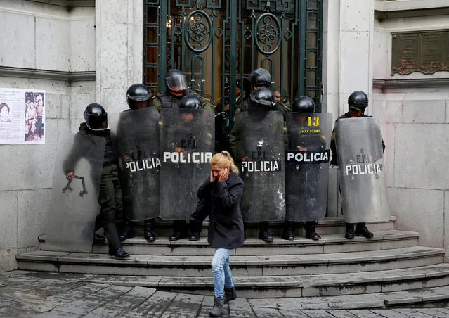 A pedestrian walks in front of riot policemen at the Bolivian  Vice Presidency during a rally protest against Bolivia's government new health care policies in La Paz, Bolivia, January 8, 2018. (Photo by David Mercado/Reuters)