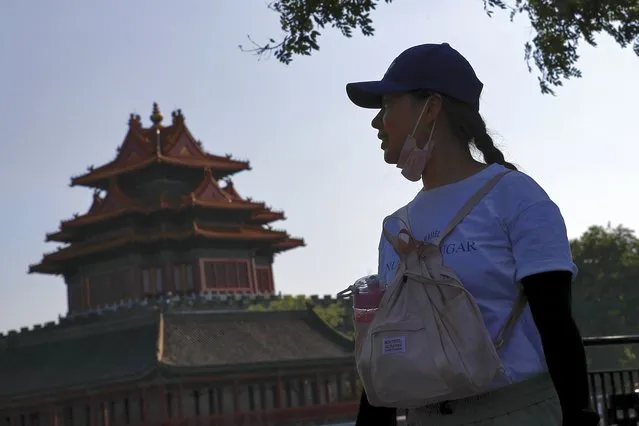 A woman puts down her face mask walks by the Turret of the Forbidden City in Beijing, Thursday, August 13, 2020. New local cases in China fell into the single digits, while Hong Kong saw another rise in hospitalizations and deaths. (Photo by Andy Wong/AP Photo)